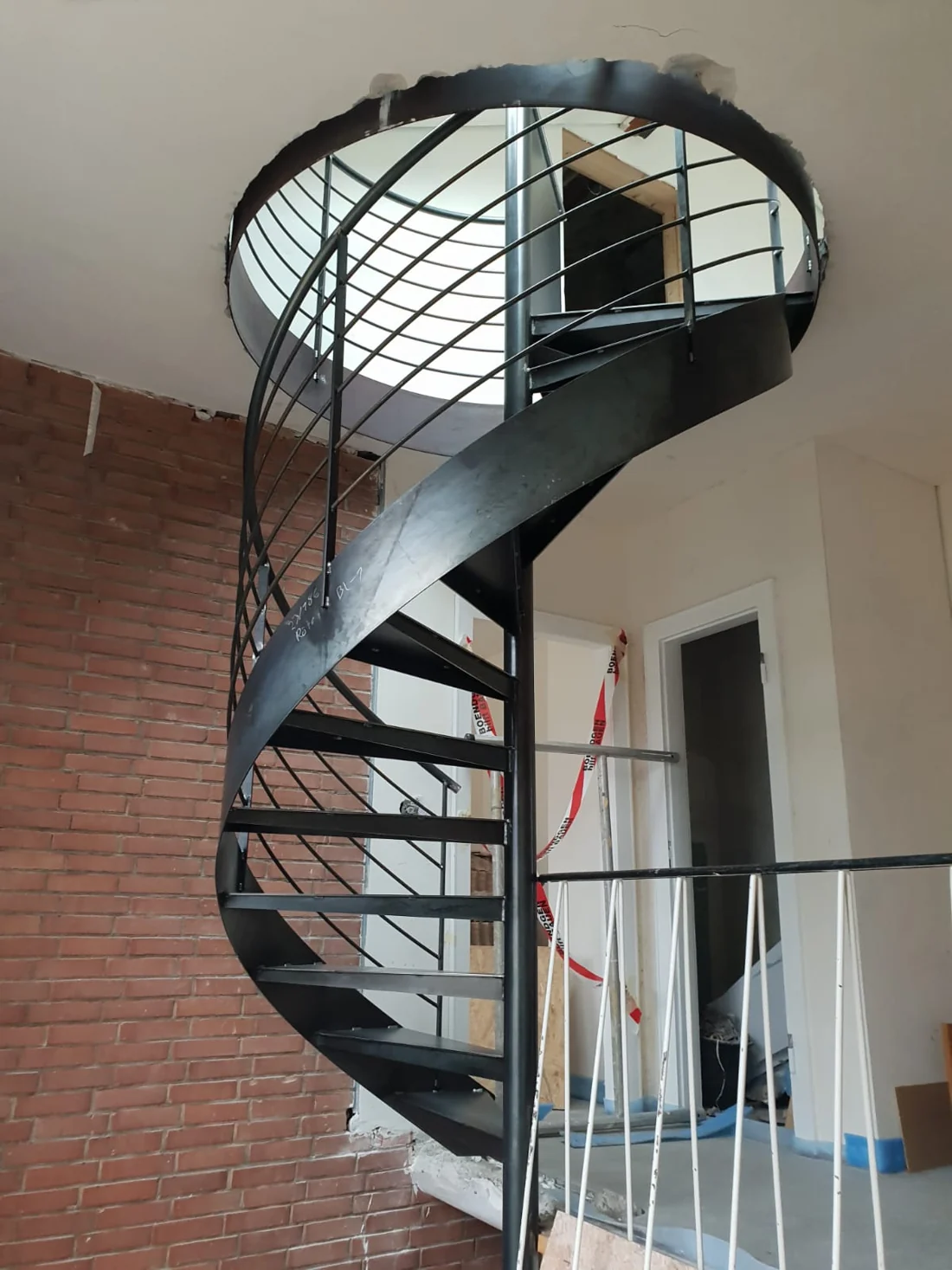 Spindeltreppe aus Stahl vor einer Backsteinwand